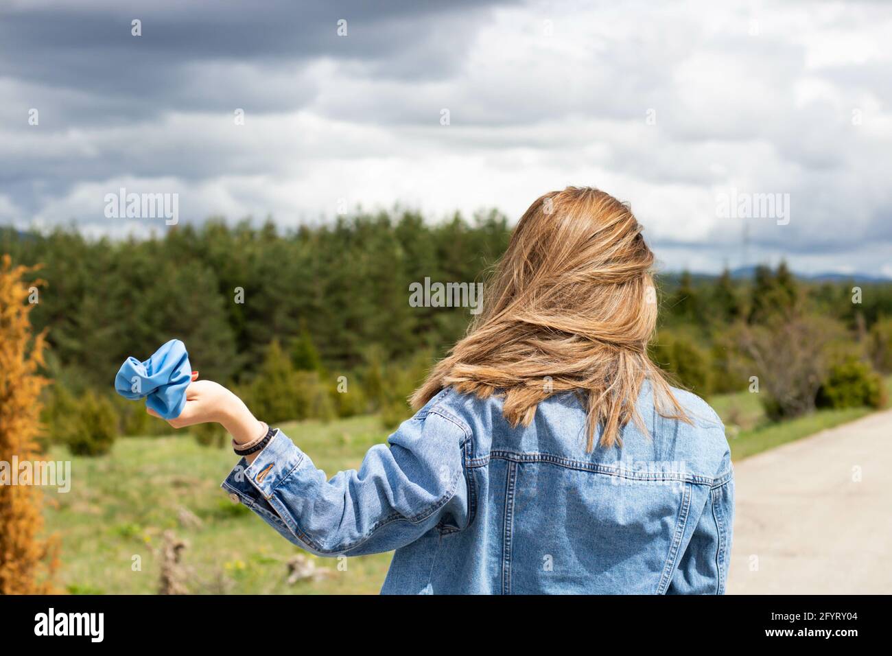 A cute female walking with a blue scrunchie in her hand Stock Photo
