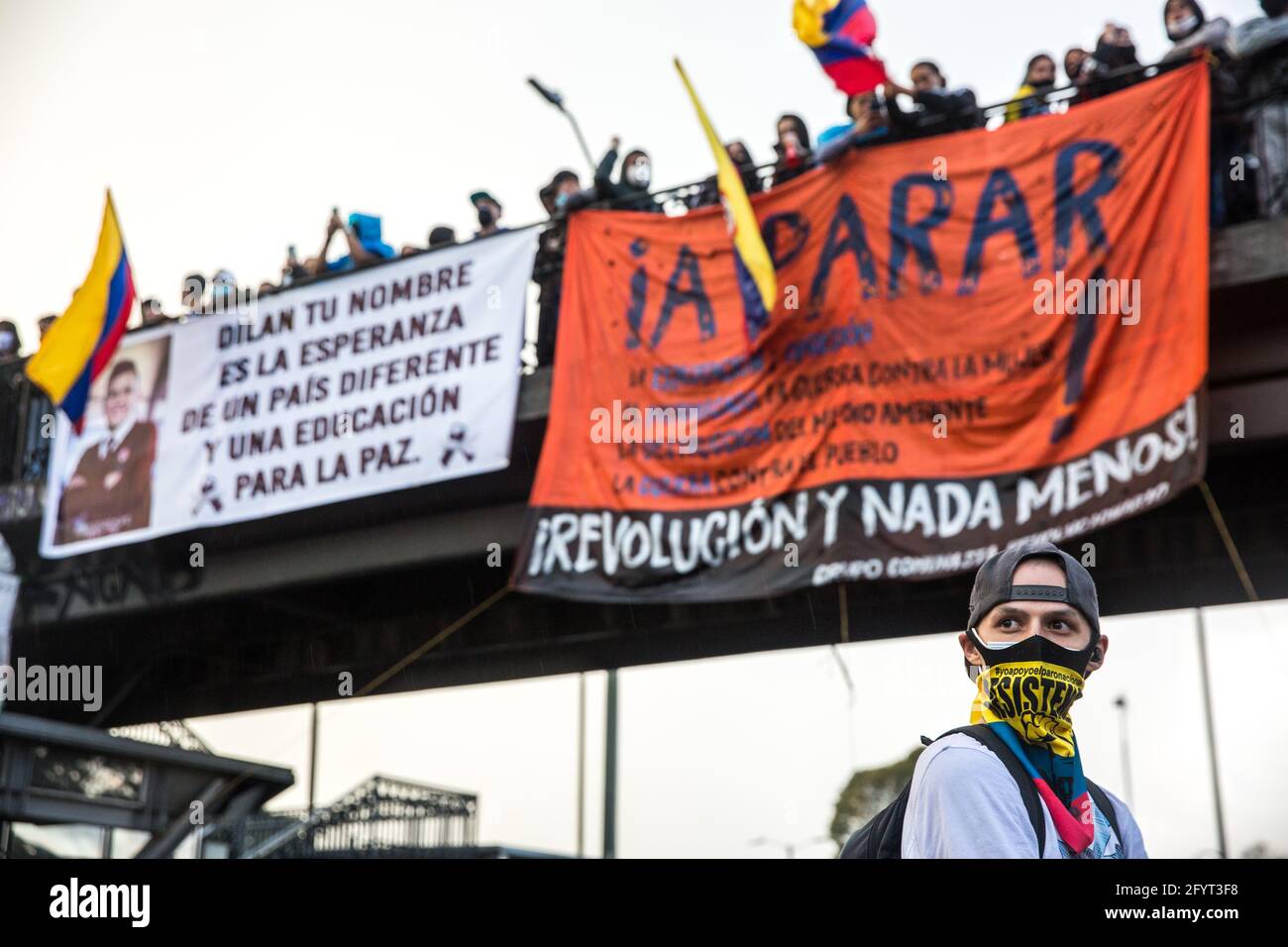 A protesters with his face covered, standing under the bridge where hang anti-government banners in Plaza de Los Heroes (Heros square). One of them commemorates the death of Dilan Cruz, a young boy killed by police in 2019 during the demonstration.On the 28th of May, a month after the national strike first began, protesters, continue to demonstrate on the streets of Bogotá and all over the country to oppose government policies. At the capital city, multiple demonstrations and marches took places during the day, with thousands of people participating in the strike. At Plaza de Los Heroes (Heros Stock Photo