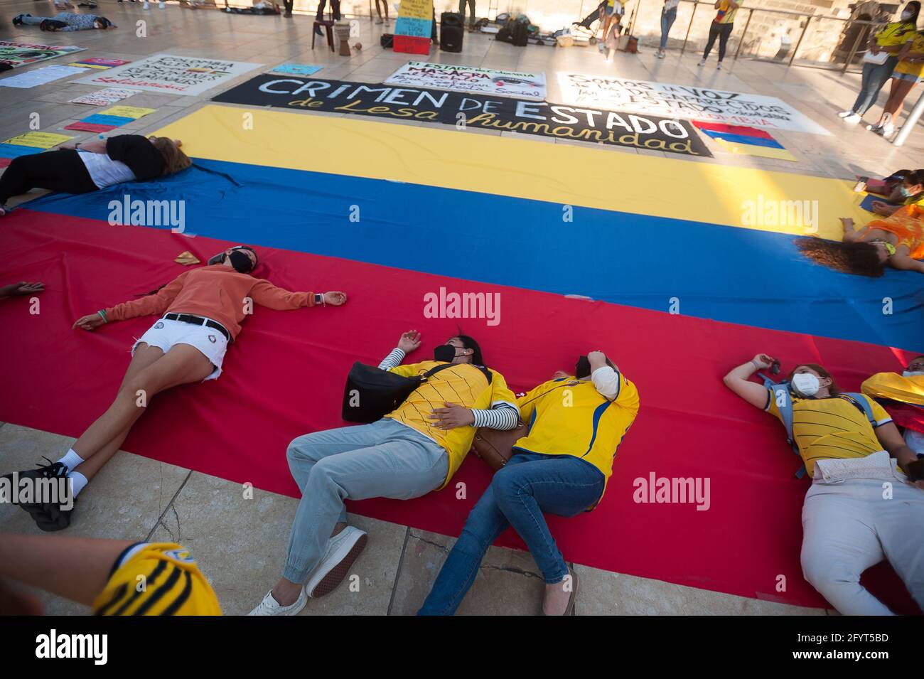 Malaga, Spain. 29th May, 2021. Colombian protesters are seen lying on a large flag as they perform during a protest on Alcazabilla street.After a month of protests following the social burst in Colombia, dozens of Colombians living in Malaga showing again their solidarity with the Colombian population and against the violence of the government of President Iván Duque. (Photo by Jesus Merida/SOPA Images/Sipa USA) Credit: Sipa USA/Alamy Live News Stock Photo