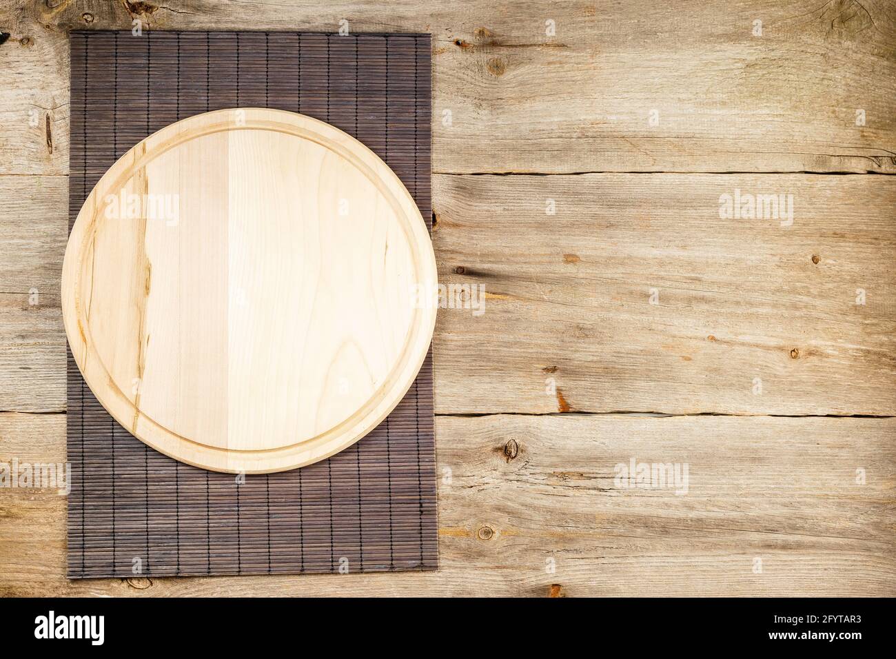 Background with wooden pizza board with bamboo table placemat over grunge rustic background Stock Photo
