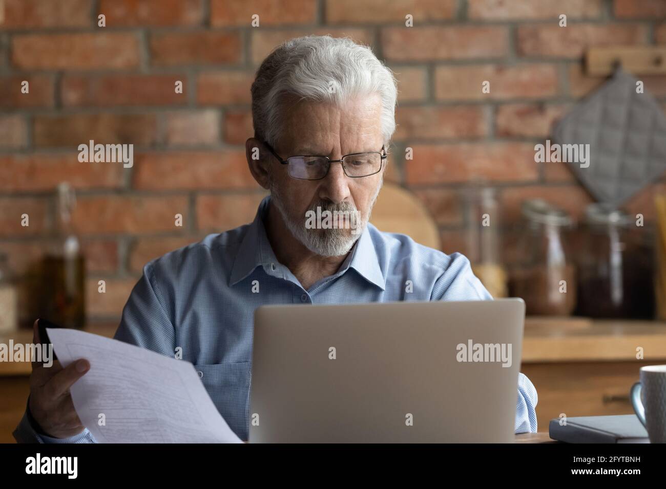 Older man holding bill makes internet payment through e-banking app Stock Photo