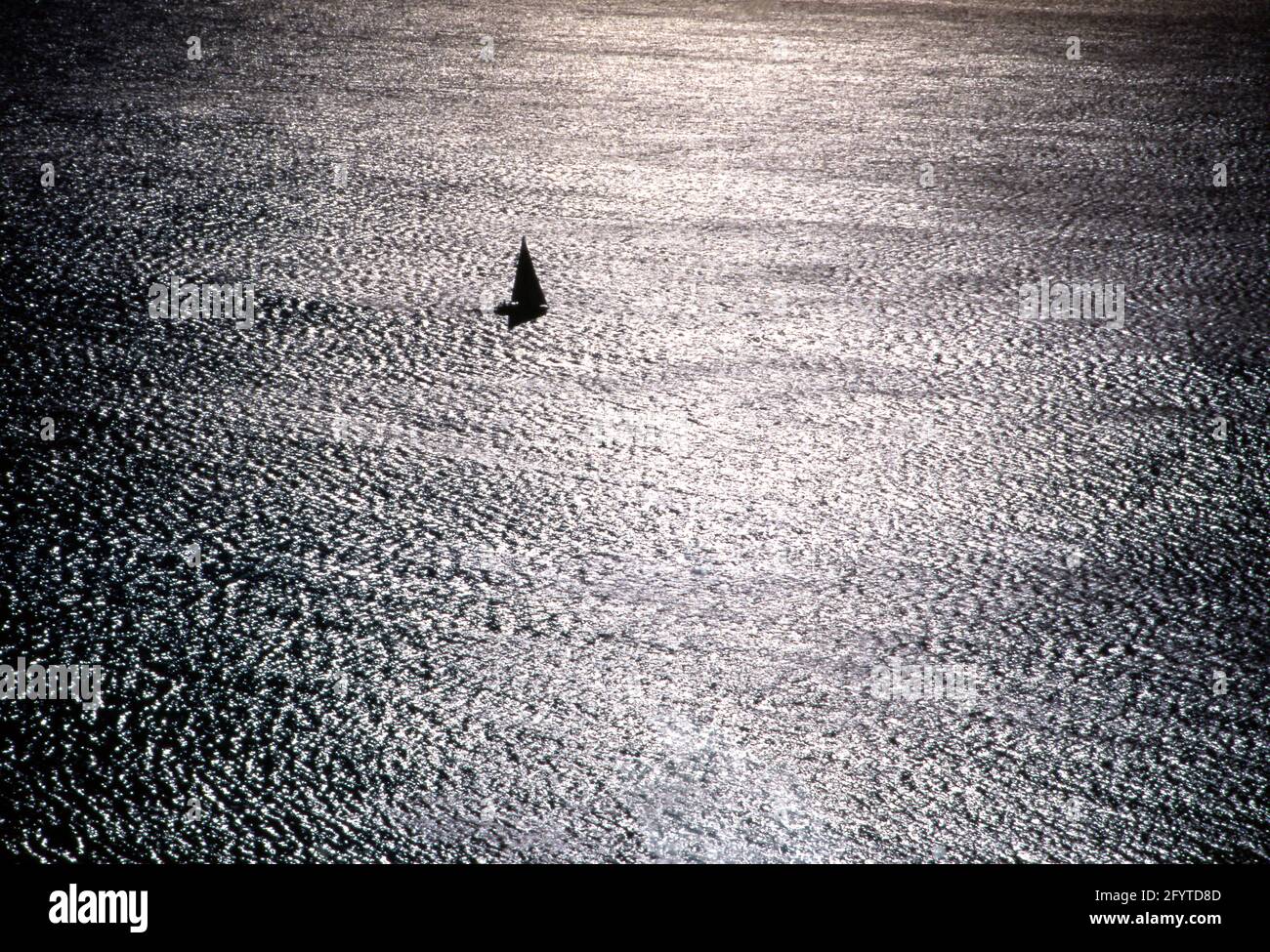 Controluce sul mare con barca a vela in navigazione Stock Photo