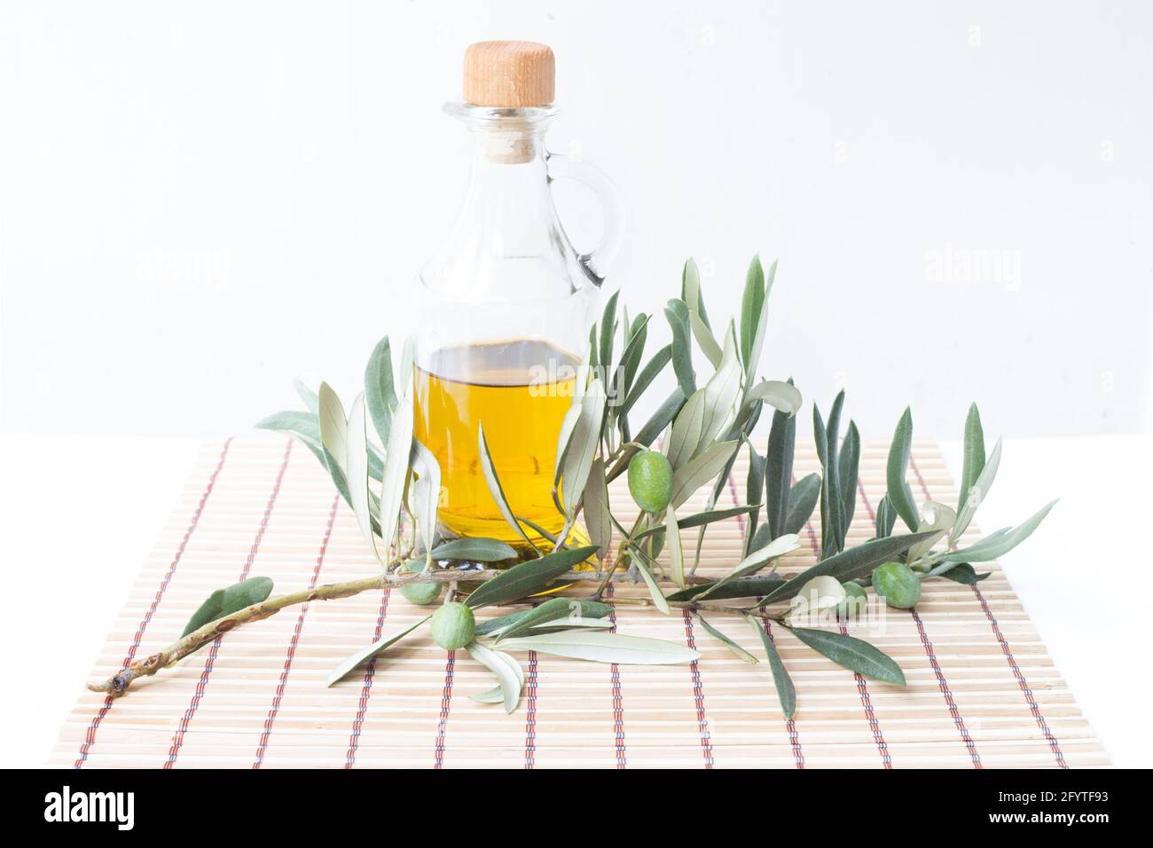 Glass bottle of olive oil and some olives with leaves isolated on a ...