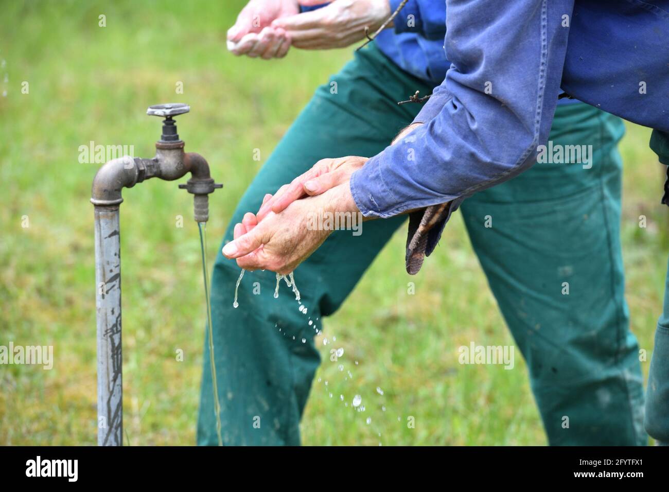 Washing hands on a green meadow from the water supply of a well Stock Photo