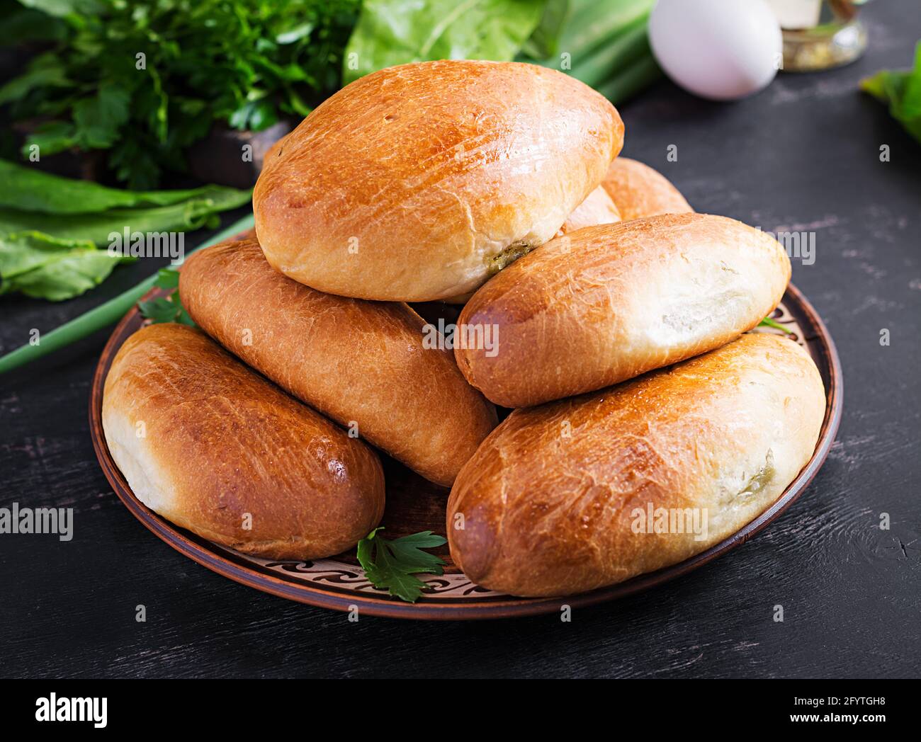 Traditional Ukrainian pies with eggs, green onion, sorrel on dark  background. Russian piroshki, homemade baked patties. Stock Photo