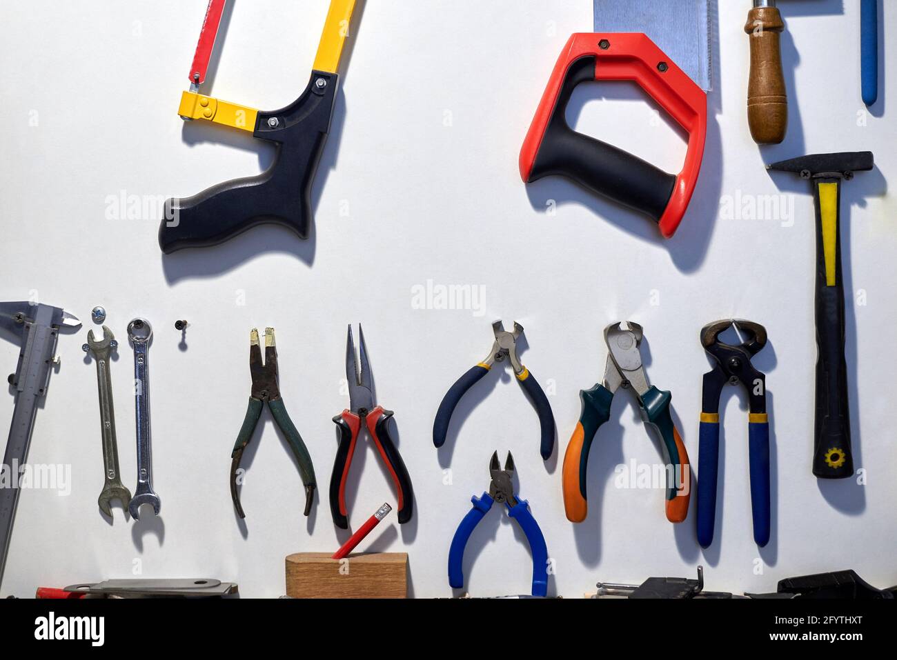 A set of different tools hanging on a white wall. Stock Photo