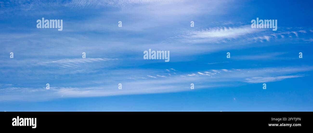 Panorama of blue sky with white clouds floating in the sky on a clear sunny warm day, summer sky landscape with blurred abstract clouds. Stock Photo