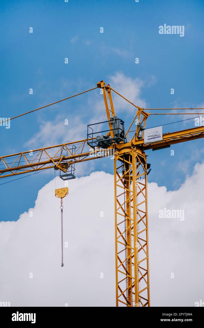A vertical low angle shot of a crane machine against the cloudy sky ...