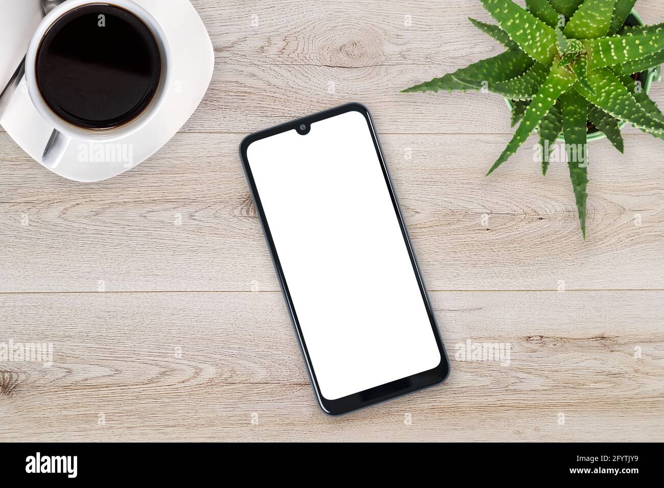 Top view of a new modern smartphone mockup with blank white screen on a wooden table with coffee and green flower (copy space). Stock Photo