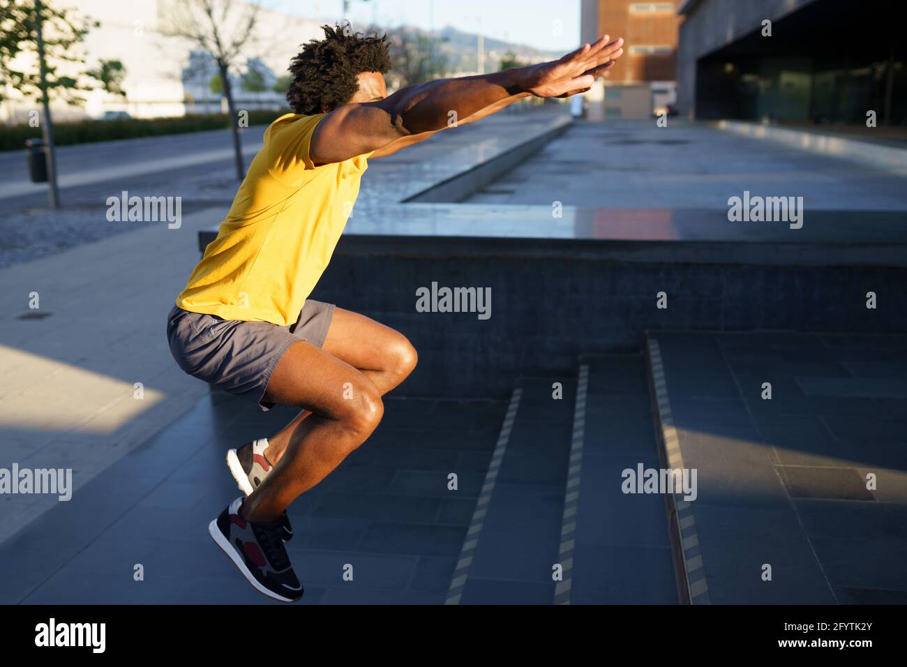 Black man doing squats with jumping on a step. Stock Photo