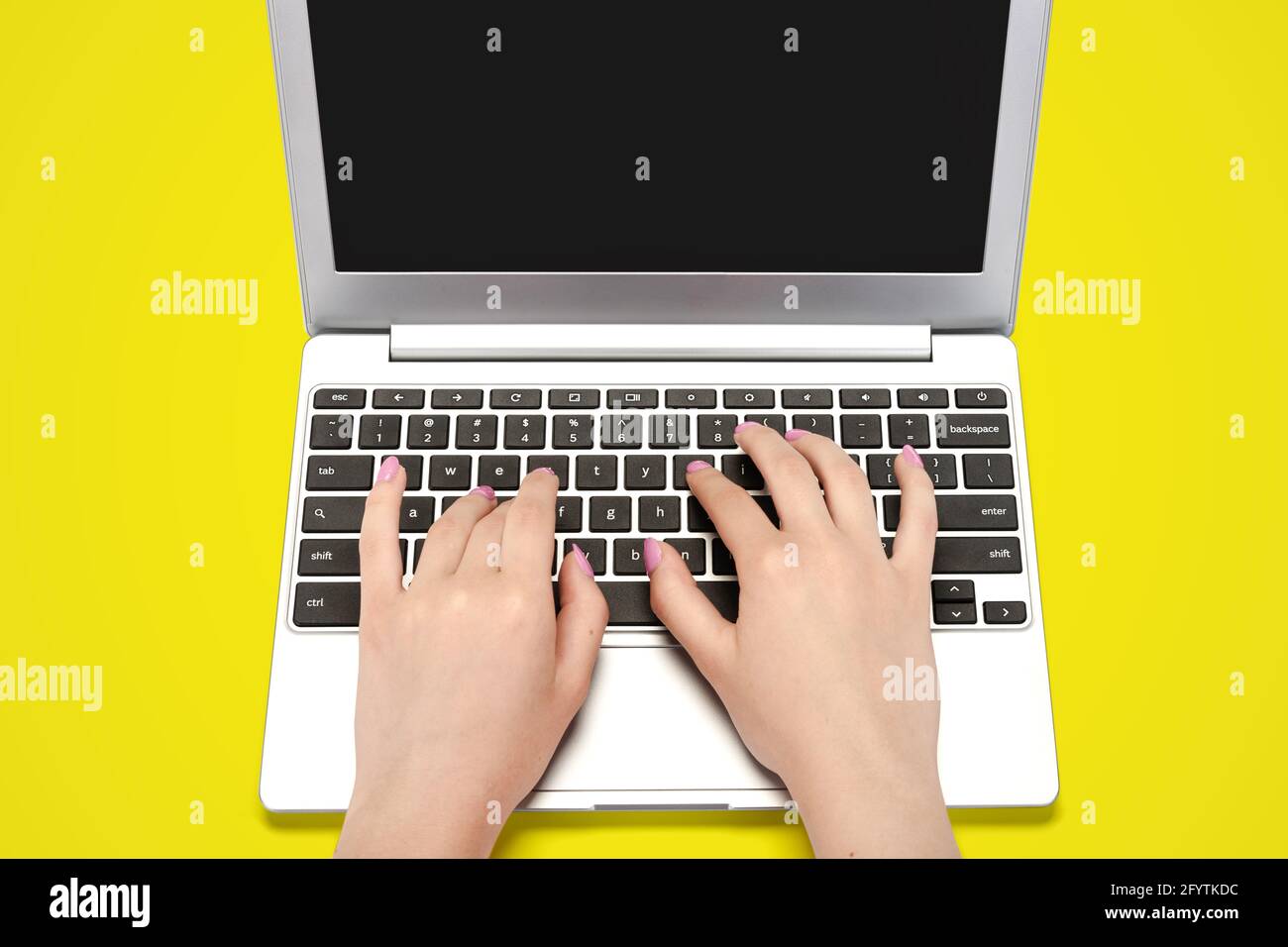 Top view image of perfect female hands typing on a laptop on a yellow background Stock Photo