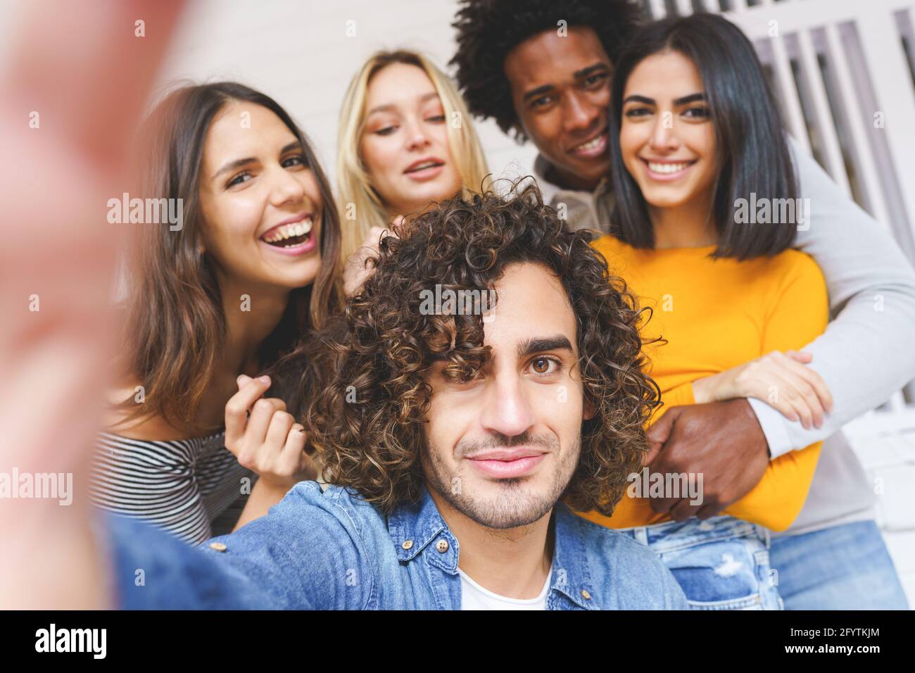 Multi-ethnic group of friends taking a selfie together while having fun ...
