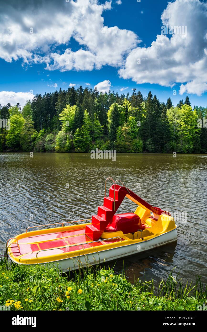 Germany, Pedal boat on water surface of a beautiful lake surrounded by green trees of forest with sunshine in summer season, perfect for holiday Stock Photo