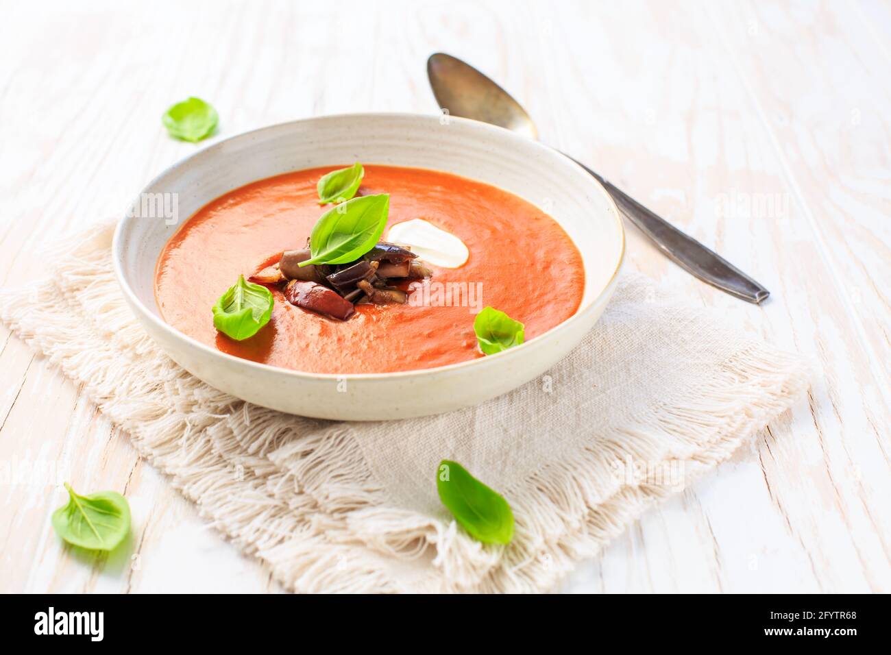 Homemade tomato soup with grilled eggplant, cream and basil on white Stock Photo