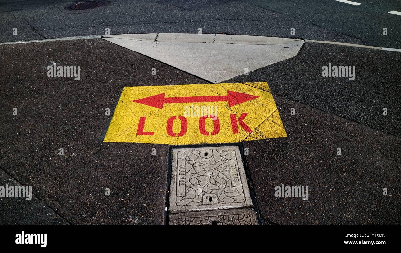 Yellow and red LOOK sign with arrows painted on the pavement in Brisbane Australia Stock Photo