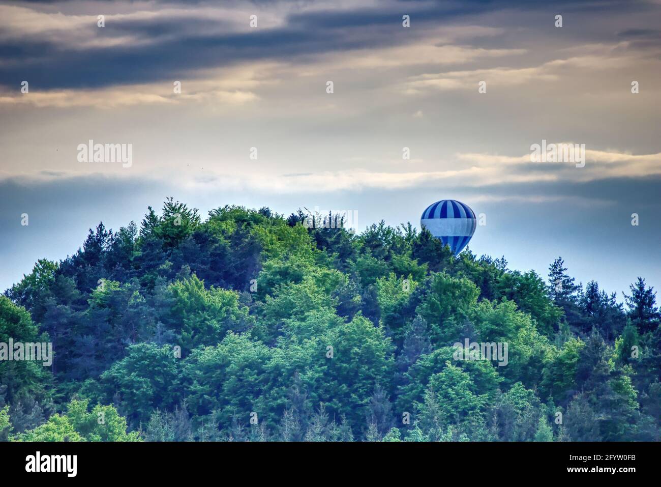 hot-air balloon behind the woodland on a mountain Stock Photo