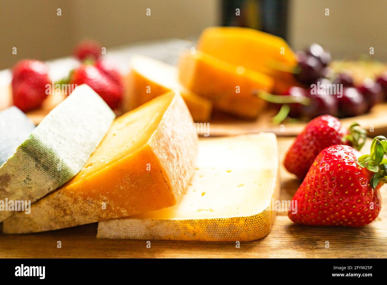 Assorted different colors craft cheese slices with berries on wooden tray background Stock Photo