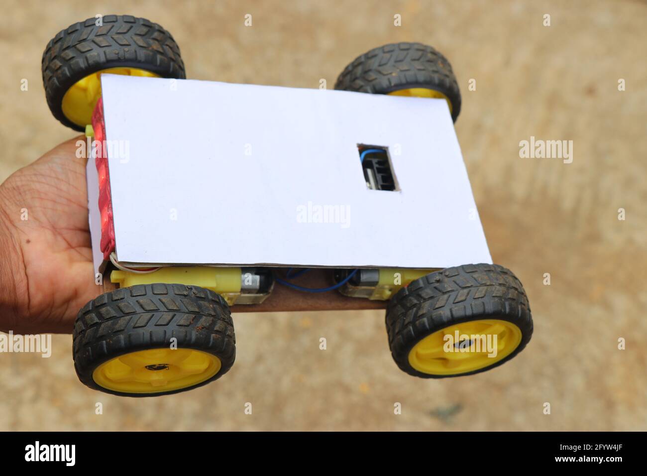 Robotic car having 4 wheels all powered by powerful plastic geared motors held in hand. Smartphone controlled robotic car project working model Stock Photo
