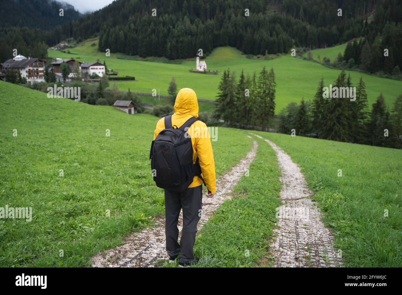 A Man with backpack on hiking trail to St. Johann church in Val di Funes valley, Dolomites, Italy, Europe Stock Photo
