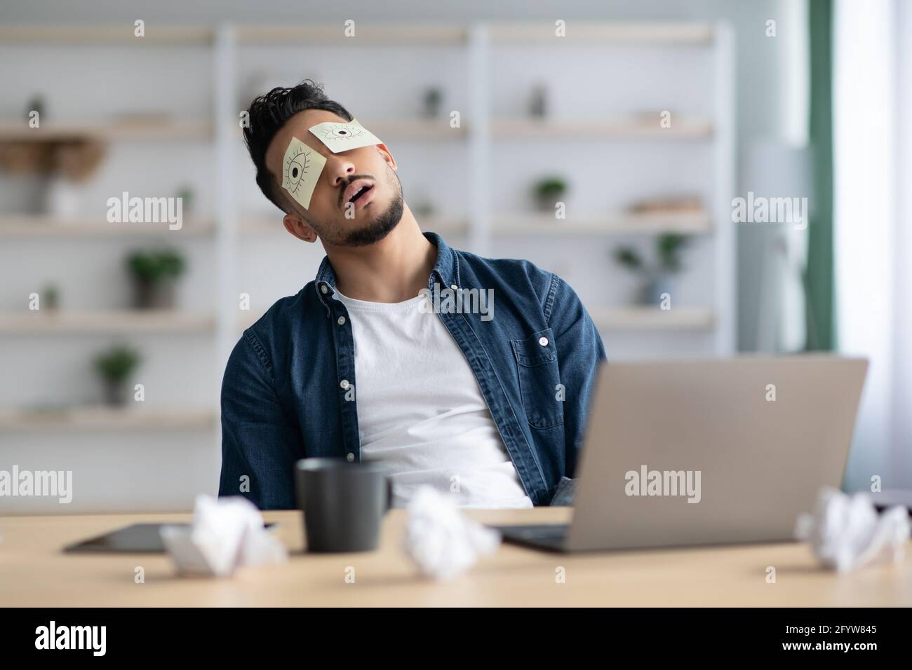 Tired arab guy with eyes drawing sleeping at workdesk Stock Photo