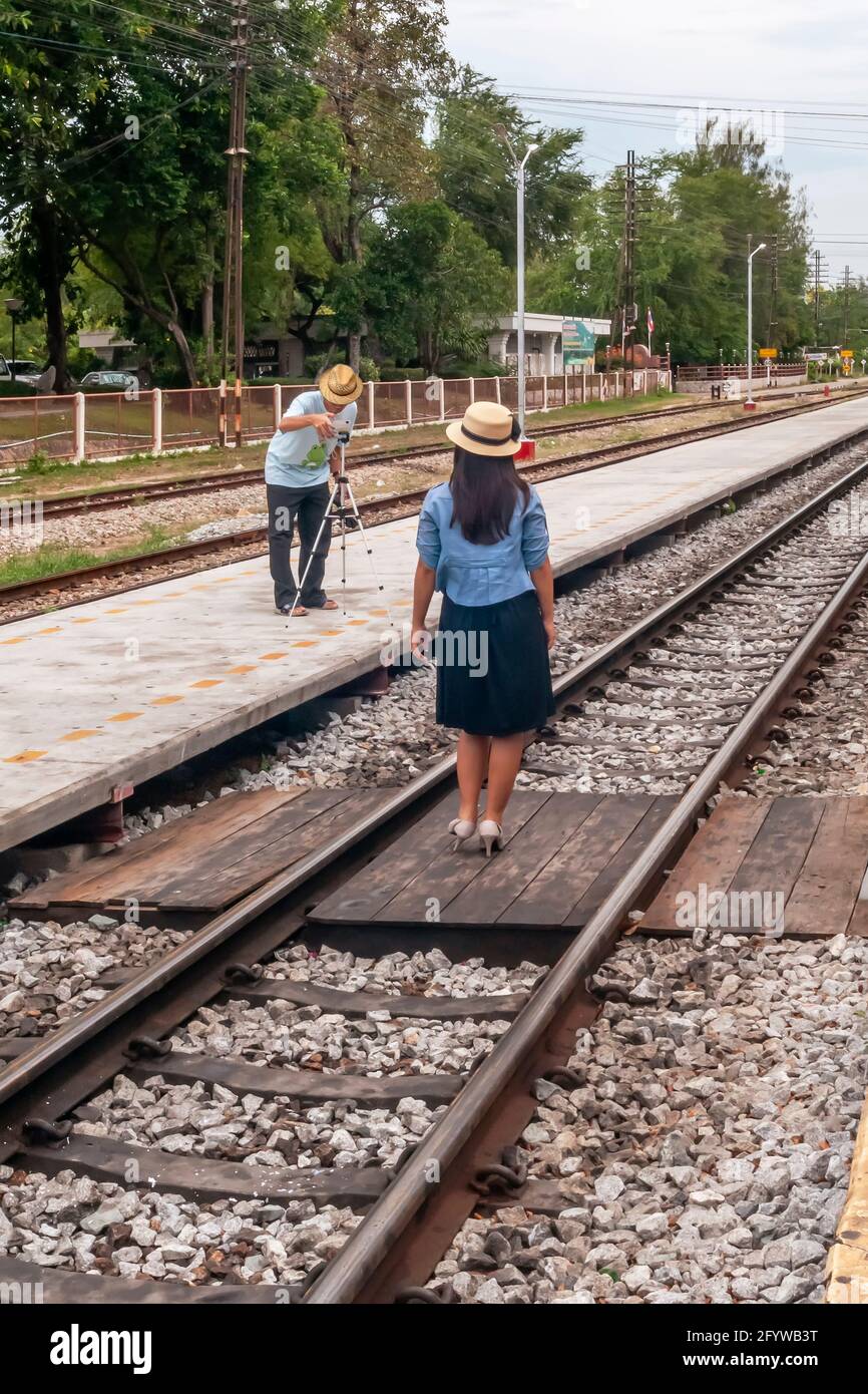 A girl is photographed dangerously on the train track in Hua Hin station, Thailand Stock Photo