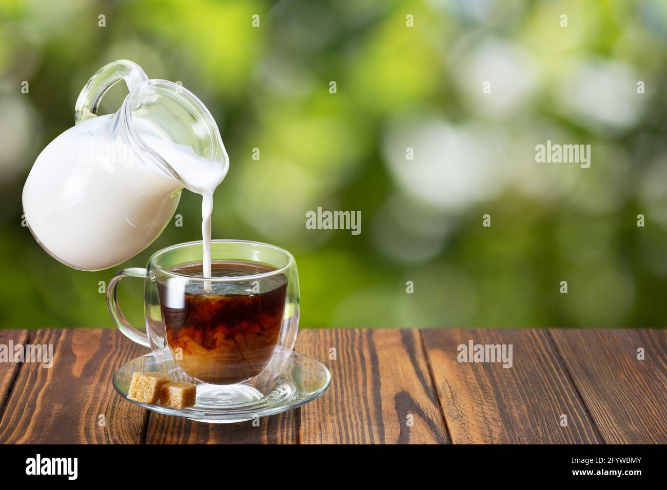 cream pouring from flying jug into cup of coffee Stock Photo