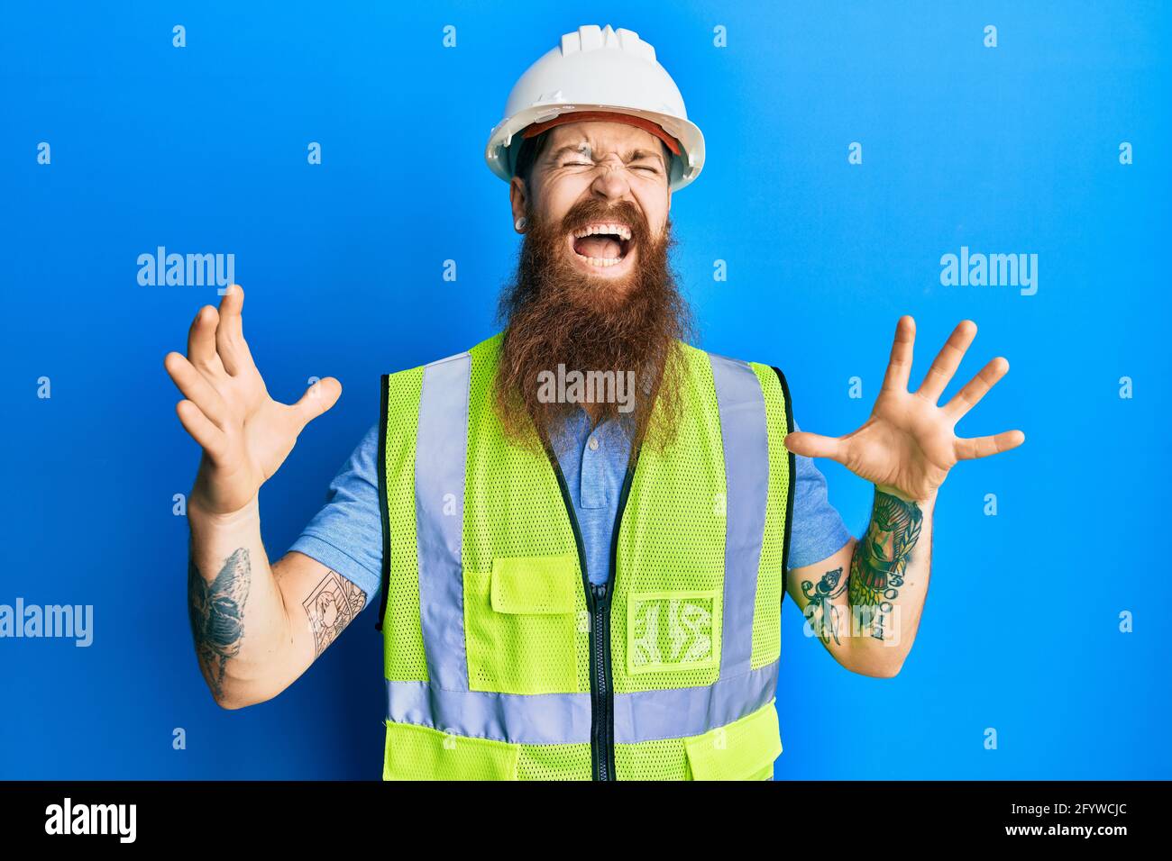 Redhead man with long beard wearing safety helmet and reflective jacket