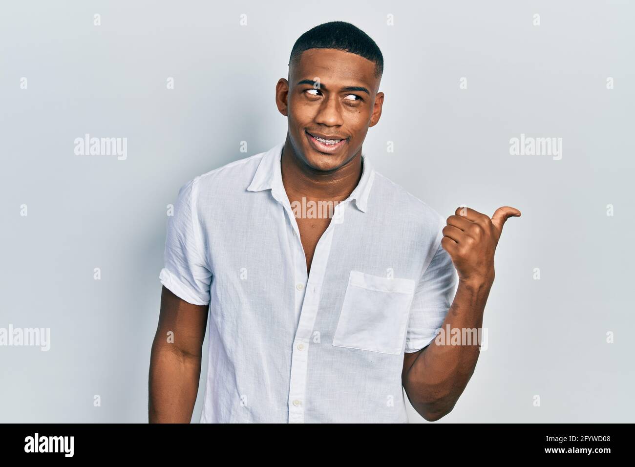 Young black man wearing casual white shirt smiling with happy face ...