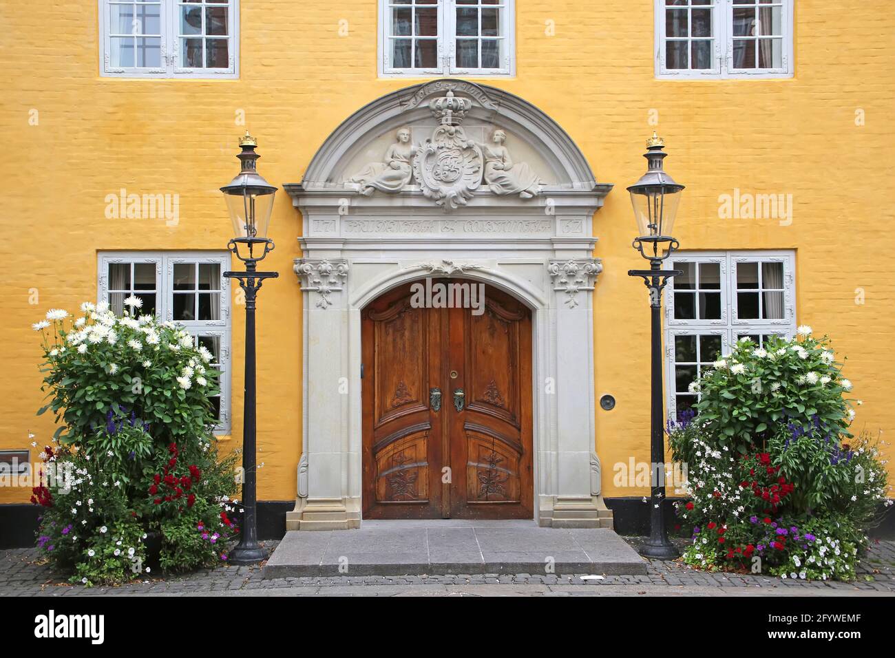 Entrance doorway of the Old City Hall. Beautiful historic yellow painted building with a wooden door in the city center, Aalborg, Denmark. Stock Photo