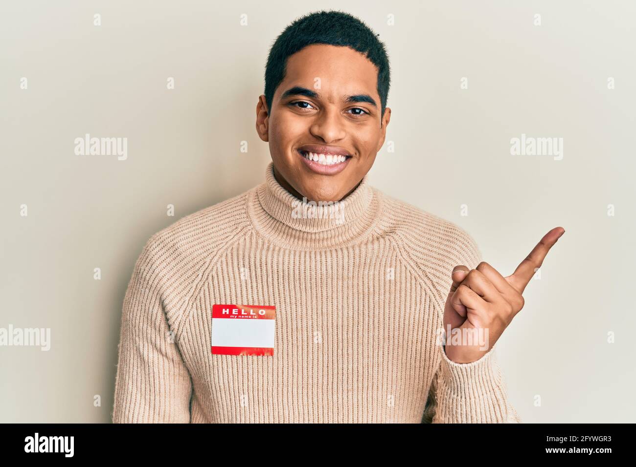 Young handsome hispanic man wearing hello my name is sticker ...