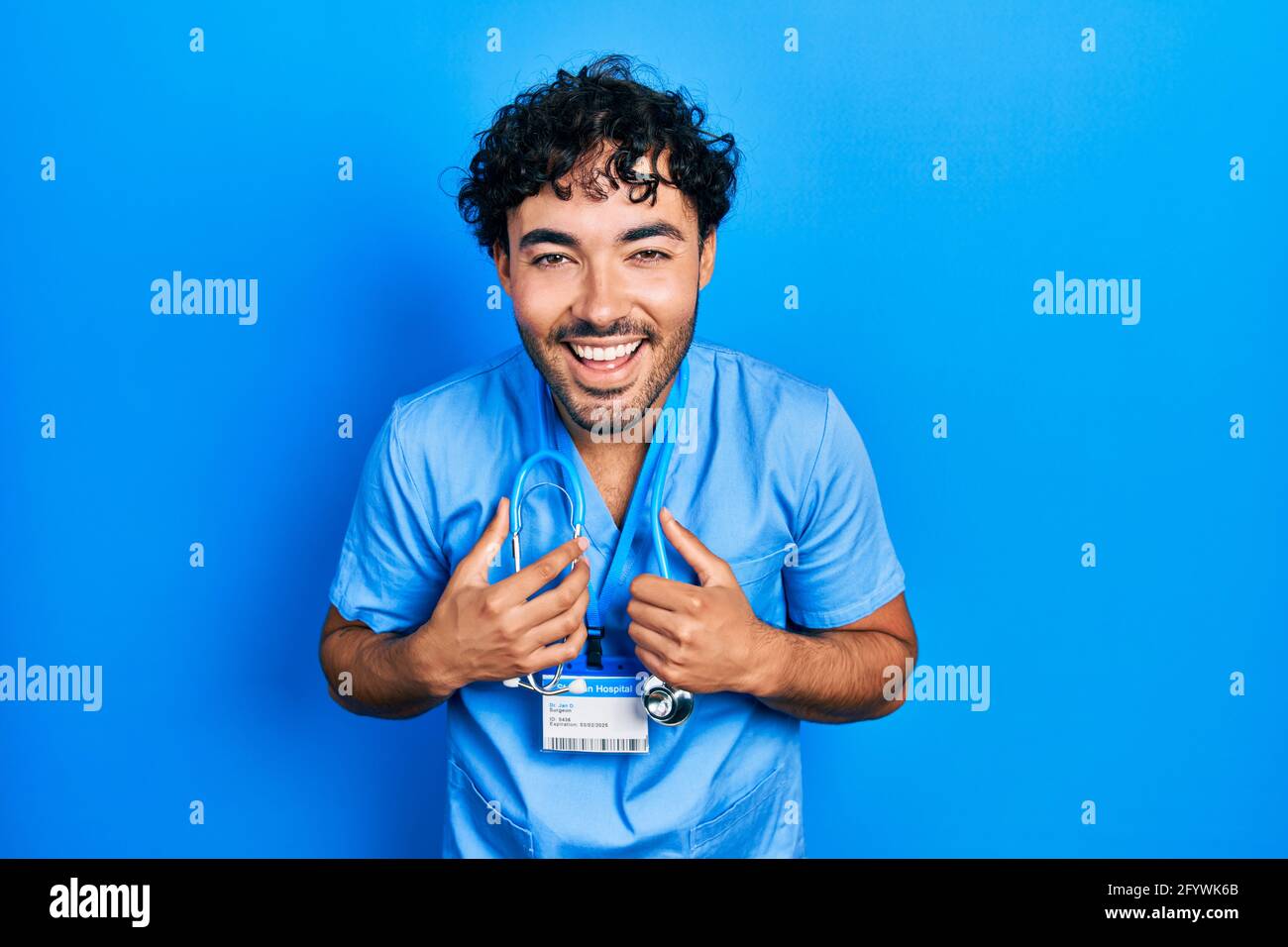Young hispanic man wearing blue male nurse uniform smiling and laughing ...