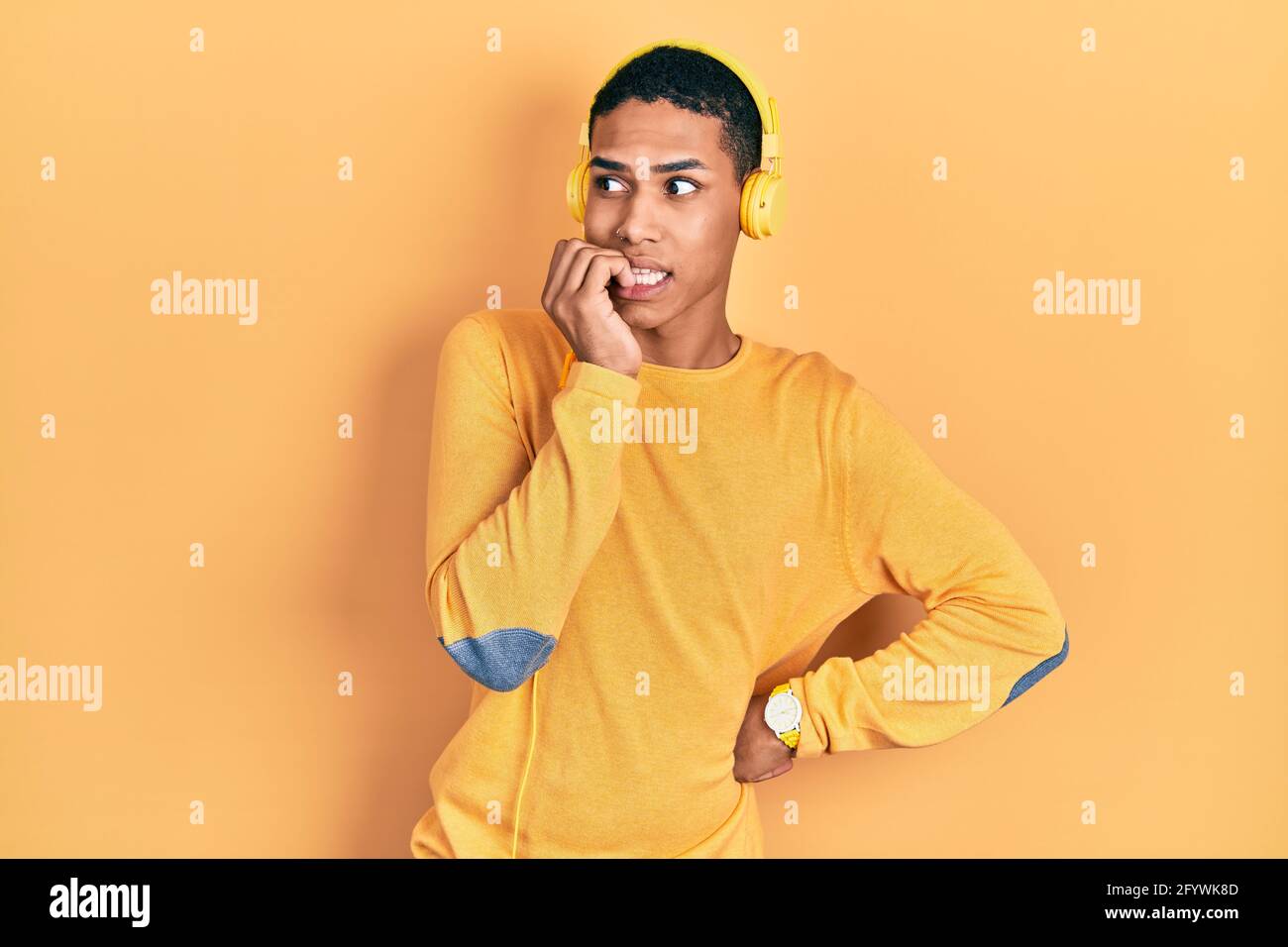 Young african american guy listening to music using headphones looking