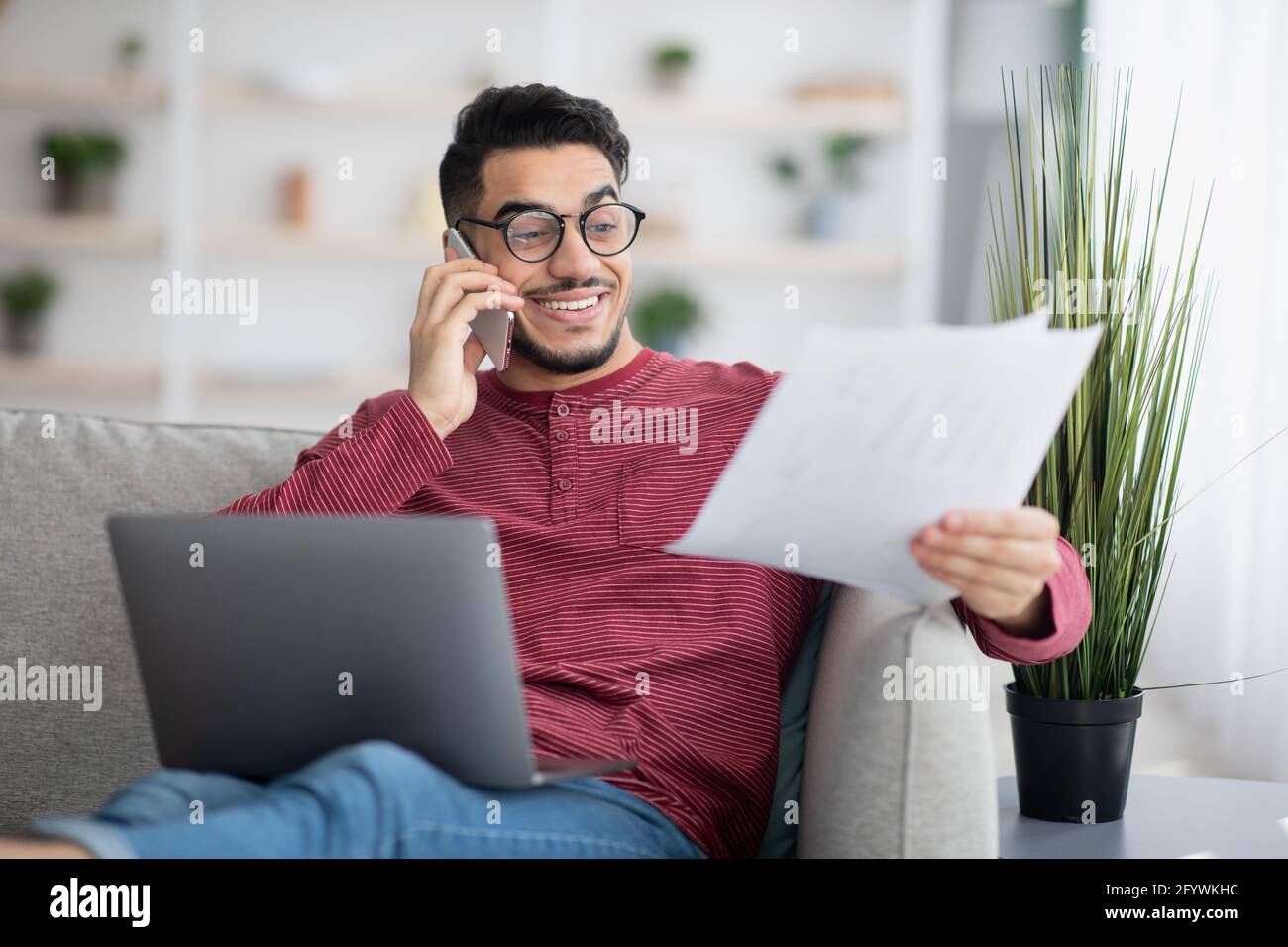 Middle-eastern man working online, using laptop and mobile phone Stock Photo