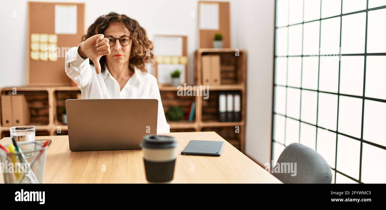 Middle age hispanic woman working at the office wearing glasses looking ...