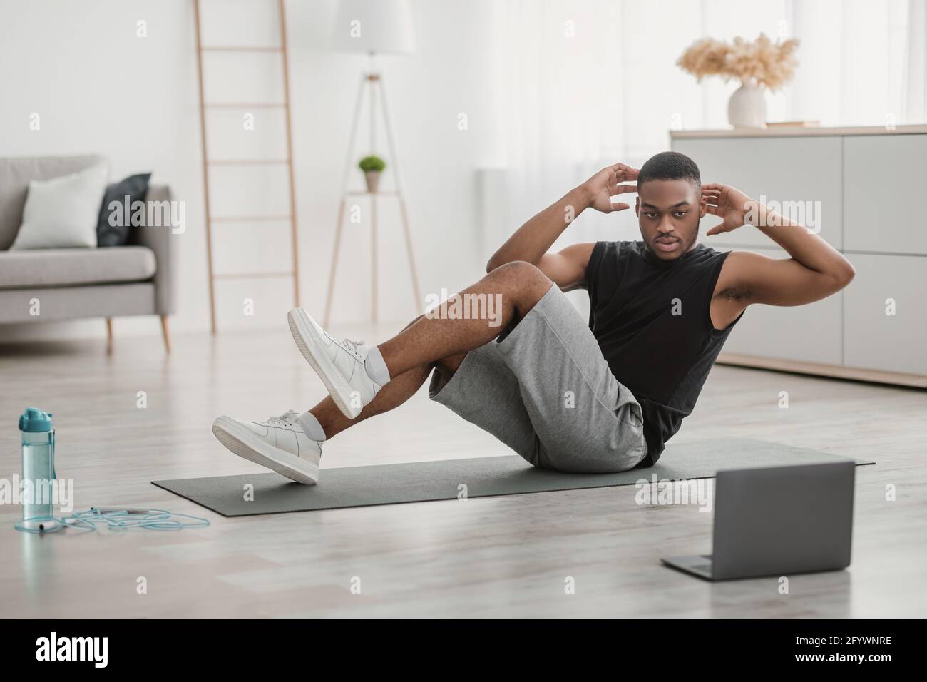 African American Guy Doing Elbow To Knee Abdominal Crunches At Laptop Indoor Stock Photo Alamy