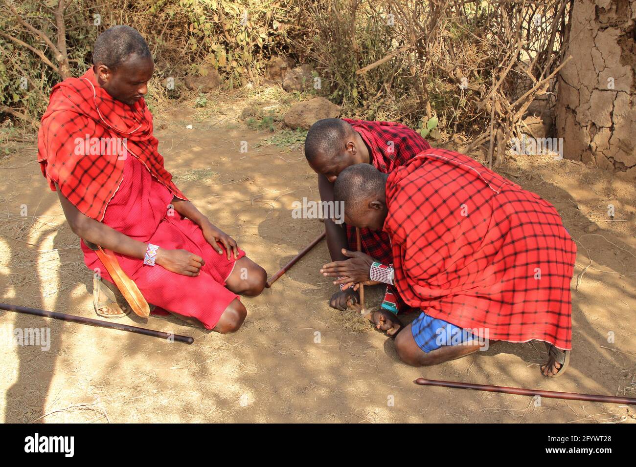 KENYA, AMBOSELI NATIONAL PARK - AUGUST 04, 2018: Three Maasai men show the traditional method to make a fire Stock Photo