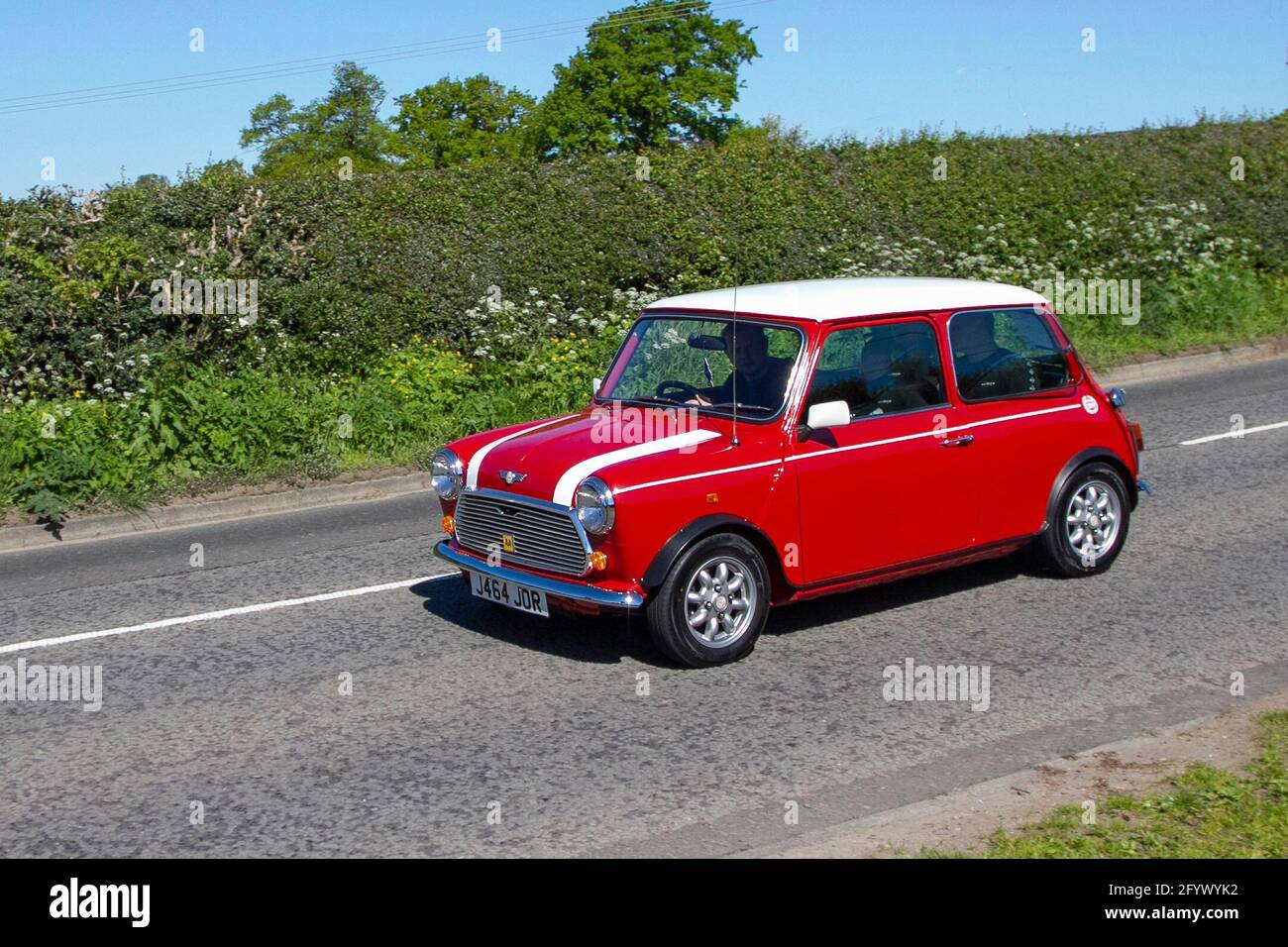 1960s Classic vintage Mini saloon with white bonnet stripes; traffic, moving vehicles, cars, vehicle driving, UK roads, motors, motoring, en-route to Capesthorne Hall classic car event, UK Stock Photo