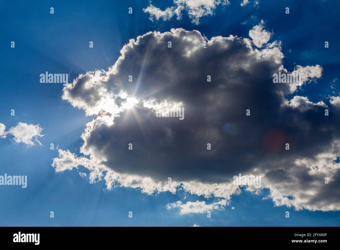 Blue sky in white clouds of cumulus clouds through which the sun shines ...