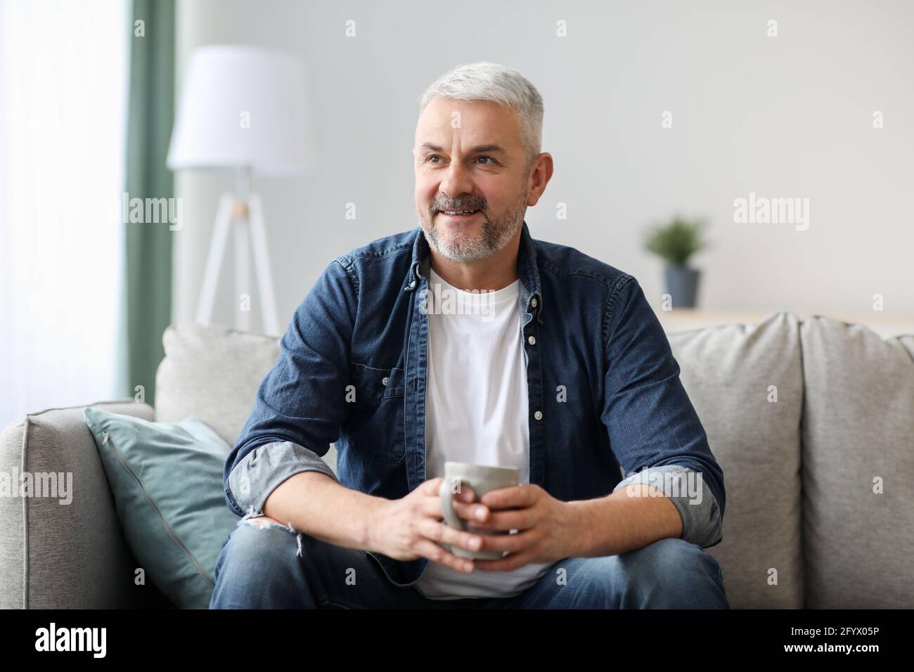 Happy old man with mug looking at copy space Stock Photo