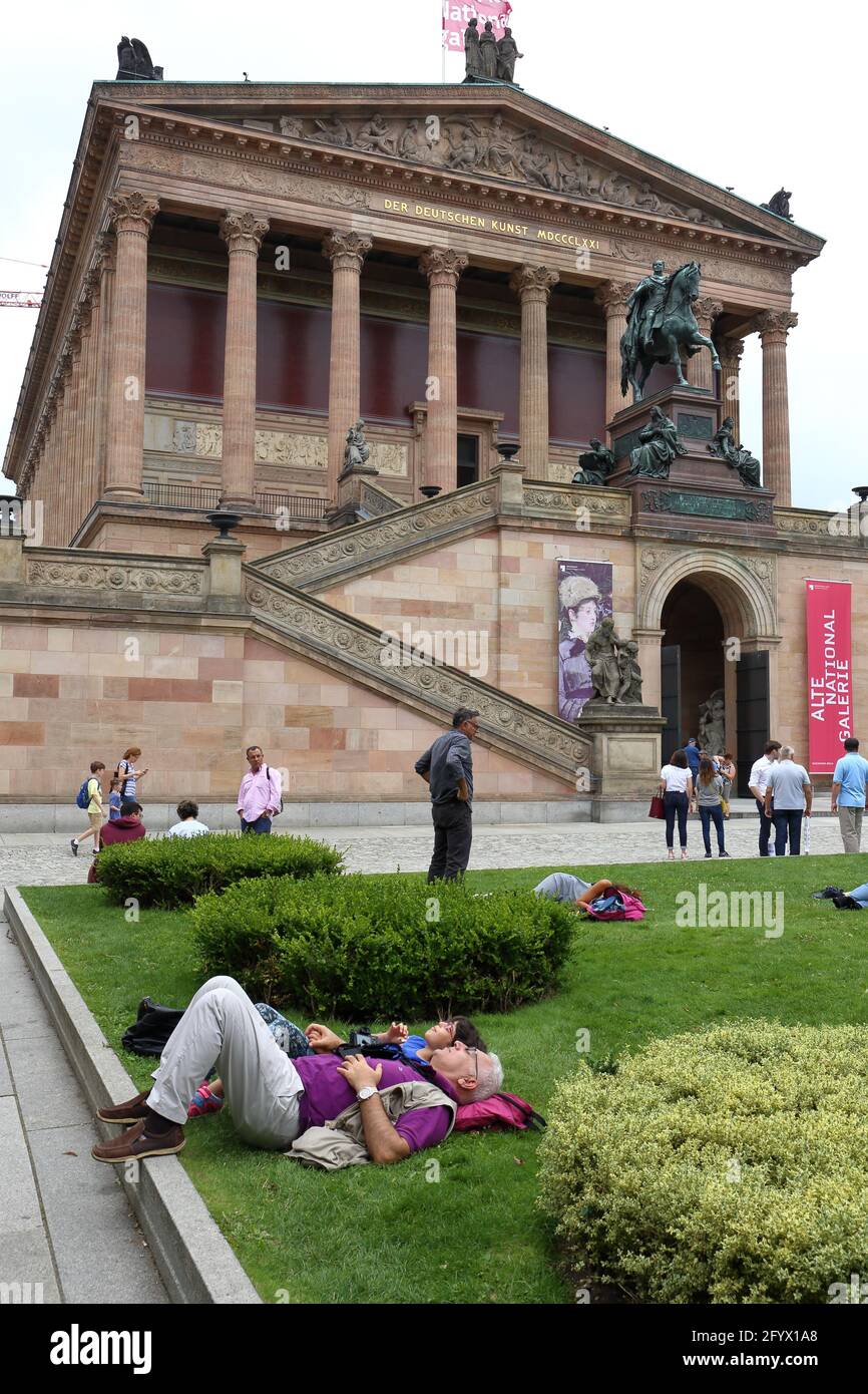 The art-weary photographer and his daughter are resting on the grass in front of the Alte National gallery Stock Photo