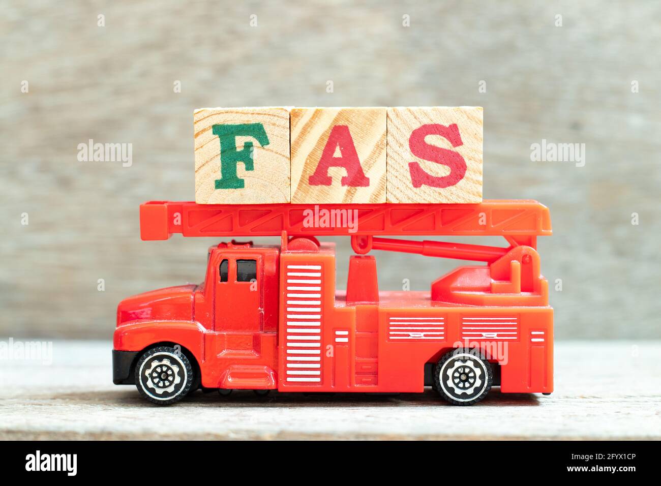 Fire ladder truck hold letter block in word FAS (Abbreviation of Fetal alcohol syndrome, Free alongside or Financial accounting standards) on wood bac Stock Photo