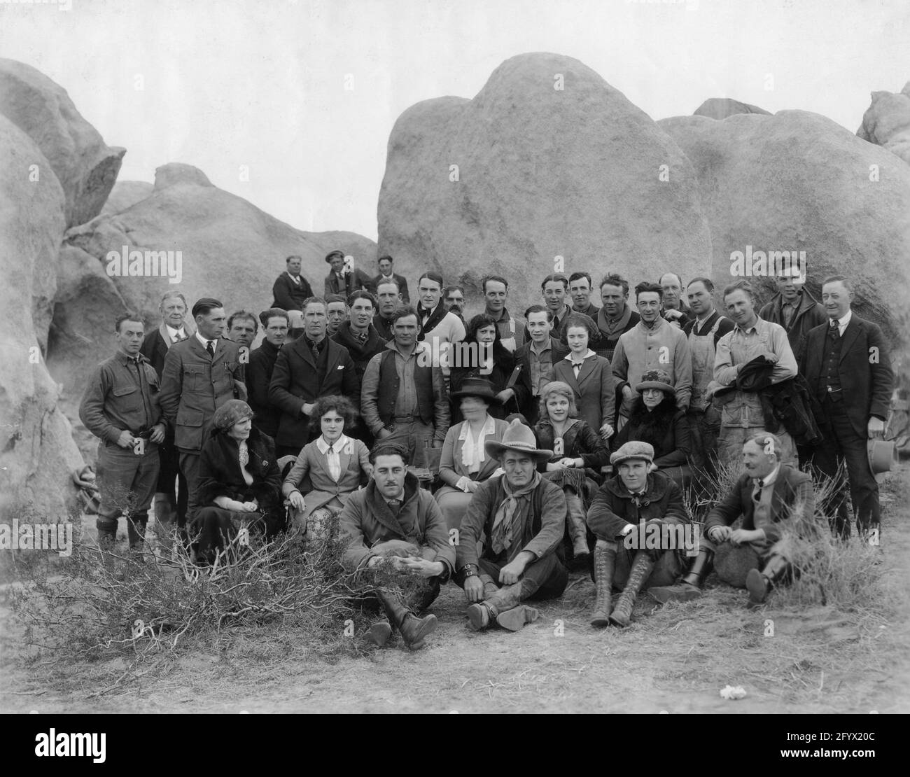 Cast and Crew Photo including a young KEN MAYNARD in his1st movie appearance in an uncredited role (4th row middle with bowtie and white sweater) and front row WILLIAM FARNUM TOM SANTSCHI Director LYNN REYNOLDS and Cinematographer DEVEREAUX JENNINGS , second row : CLAIRE ADAMS (left behind Farnum) and WANDA HAWLEY (right behind Santschi), 3rd row CHARLES LE MOYNE (behind Adams) taken on location at Victorville San Bernardino County California for BRASS COMMANDMENTS 1923 novel Charles Alden Seltzer Fox Film Corporation Stock Photo