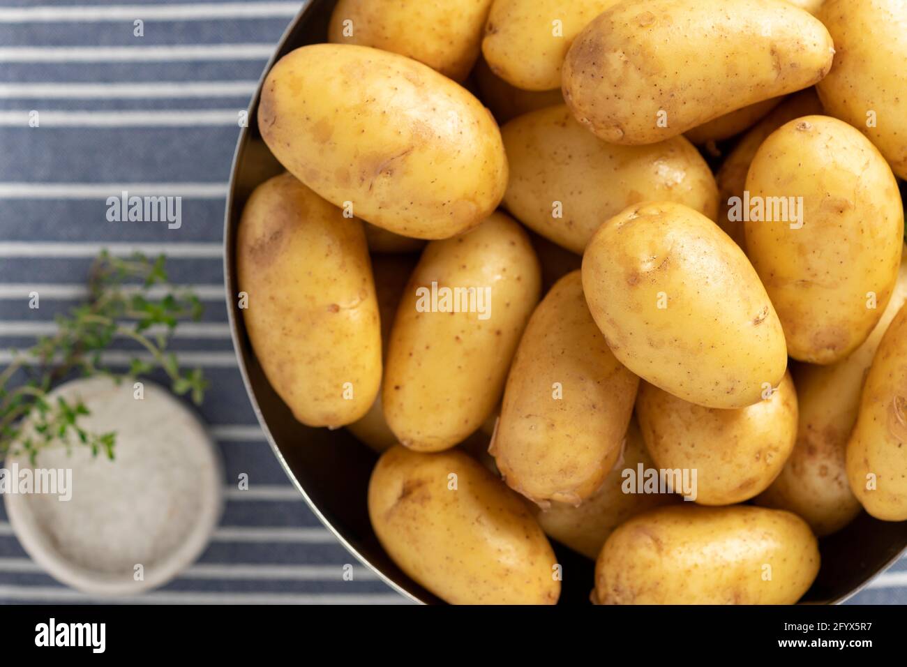 close-up of uncooked potatoes, thyme and salt. ingredients for cooking. view from above. horizontal image Stock Photo