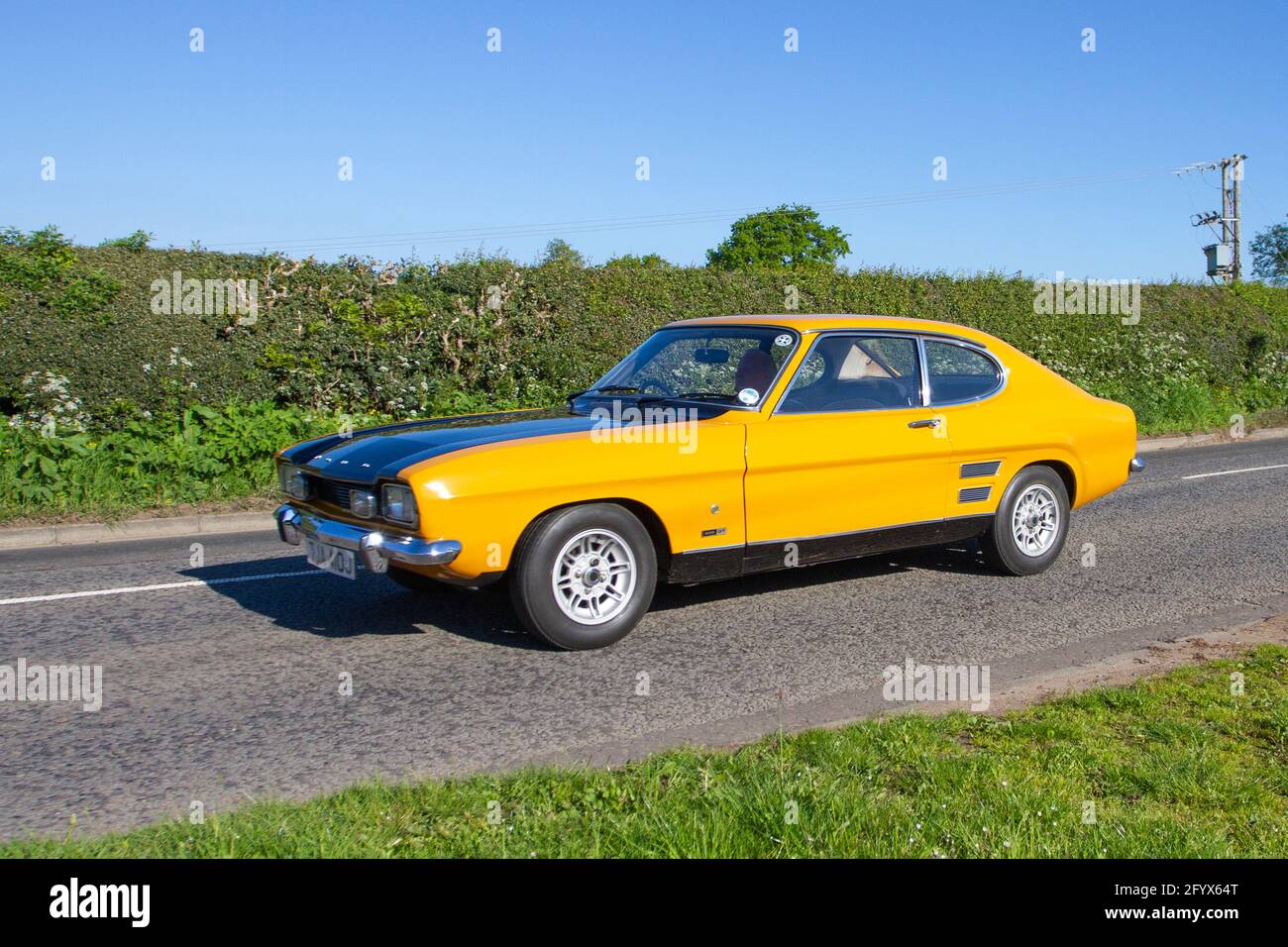1971 70s seventies yellow Ford Capri 1600 GL 2dr; Vehicular traffic, moving vehicles, cars, vehicle driving on UK roads, motors, motoring  en-route to Capesthorne Hall classic May car show, Cheshire, UK Stock Photo