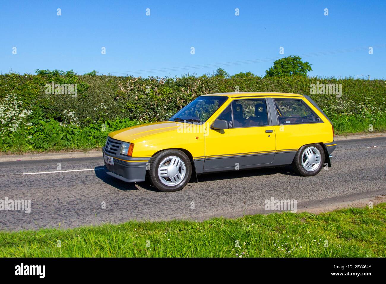 1983 80s eighties yellow Vauxhall Nova SR; Vehicular traffic, moving vehicles, cars, vehicle driving on UK roads, motors, motoring  en-route to Capesthorne Hall classic May car show, Cheshire, UK Stock Photo