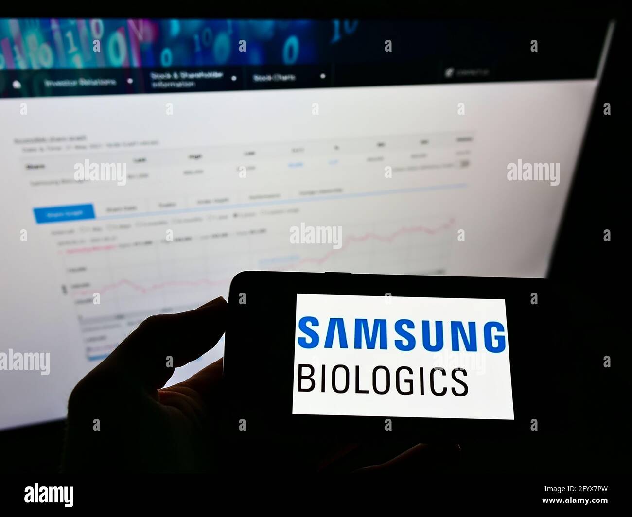 Person holding mobile phone with logo of biotechnology company Samsung Biologics Co. Ltd. on screen in front of webpage. Focus on cellphone display. Stock Photo