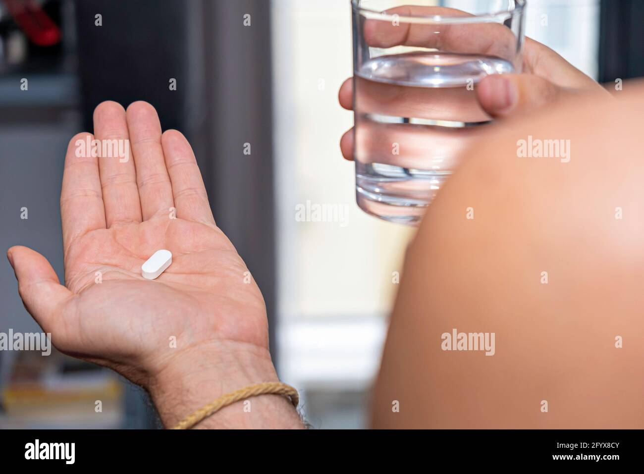 close up of male hands holding pill capsule vitamin supplement with glass of water close up Stock Photo