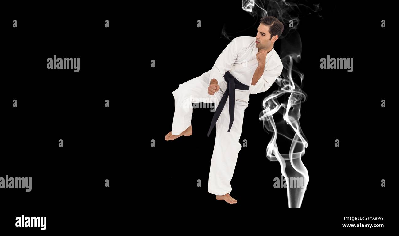 Composition of male martial karate artist with black belt kicking over smoke and copy space Stock Photo