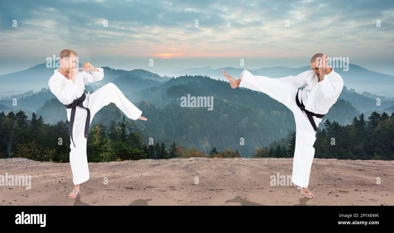 Composition of two male martial karate artists with black belt practicing in mountains Stock Photo