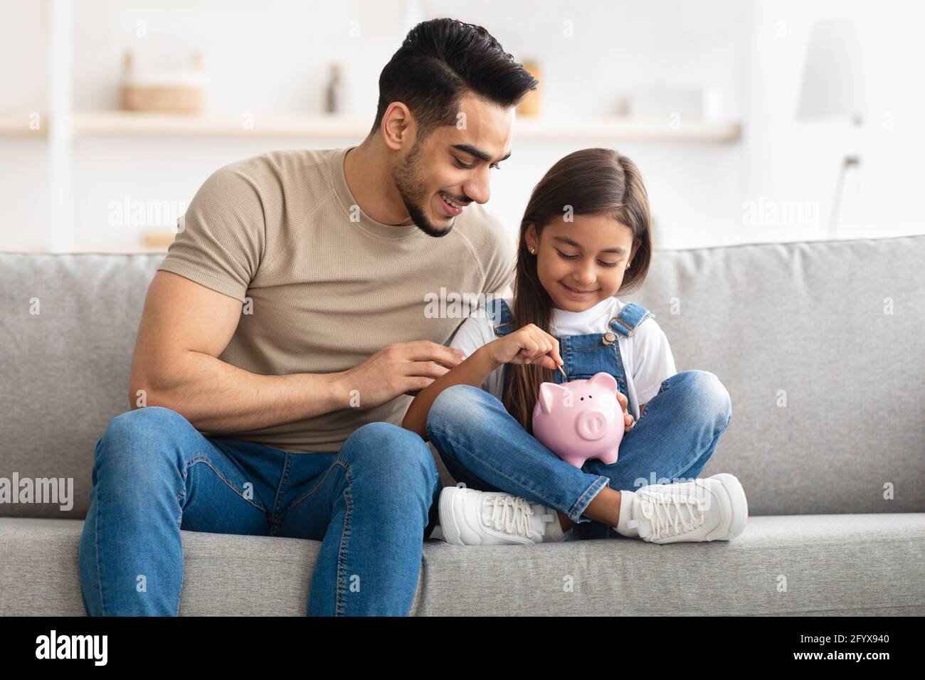 Little girl and dad saving money in piggy bank Stock Photo - Alamy